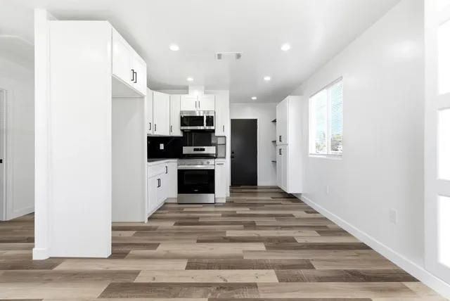 a view of an empty room with wooden floor and a window