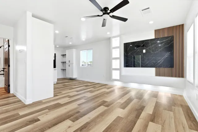 a view of empty room with wooden floor and fan