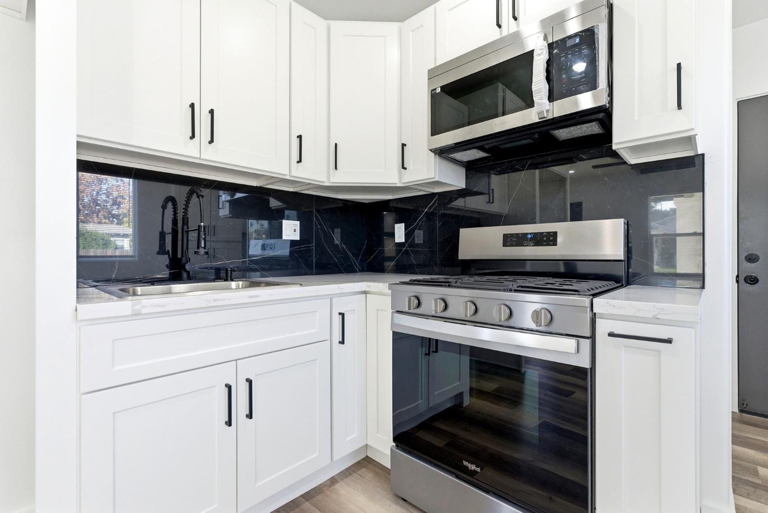 3763 East Verrue Avenue Fresno, CA 93702 - Photo 8 of 24 a kitchen with stainless steel appliances granite countertop a stove microwave and oven