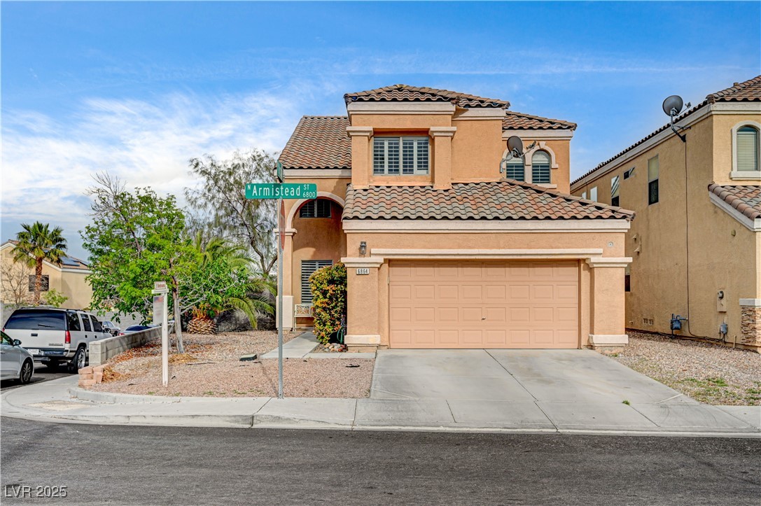View of front of home featuring stucco siding, an attached garage, a tiled roof, and concrete driveway
