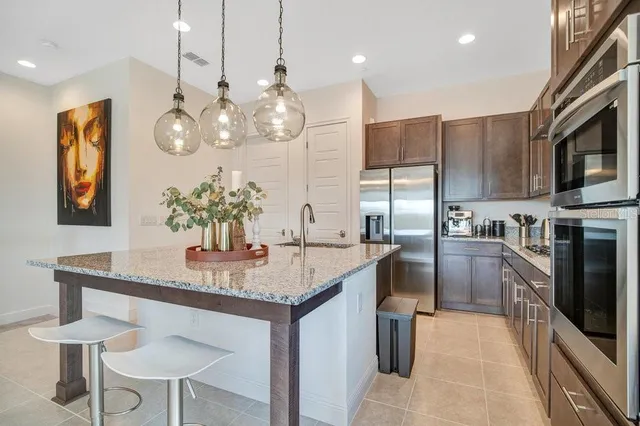 a kitchen with stainless steel appliances kitchen island granite countertop a table chairs and a refrigerator