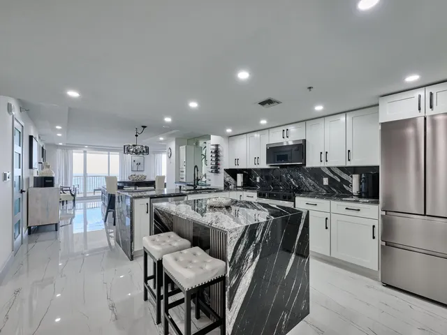 a kitchen with stainless steel appliances granite countertop a stove top oven a sink dishwasher and white cabinets with wooden floor