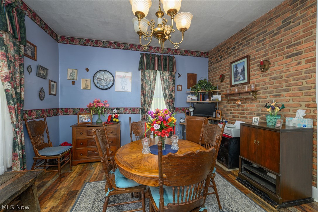 79405 Freeport Tippecanoe Road Tippecanoe, OH 44699 - Photo 24 of 42 Dining room with dark hardwood / wood-style floors, brick wall, and a chandelier