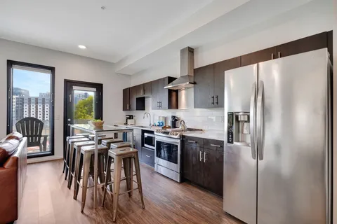 a kitchen with stainless steel appliances a table chairs refrigerator and wooden floor