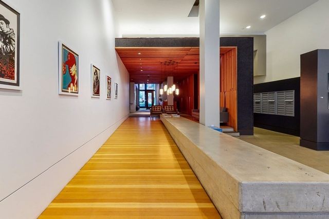 a view of a hallway with wooden floor and a bathroom