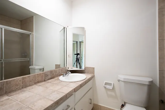 a bathroom with a granite countertop sink toilet and shower