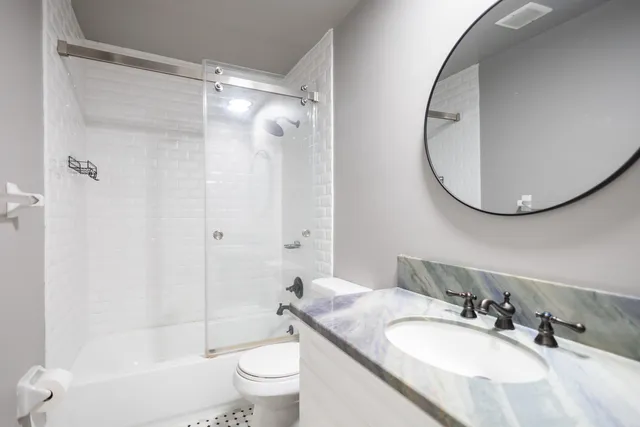 a bathroom with a granite countertop sink toilet and shower