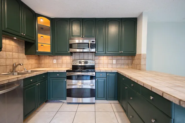 a kitchen with stainless steel appliances granite countertop a sink stove and cabinets