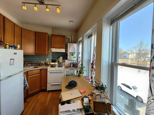 a kitchen with a stove a refrigerator sink dishwasher and cabinets with wooden floor