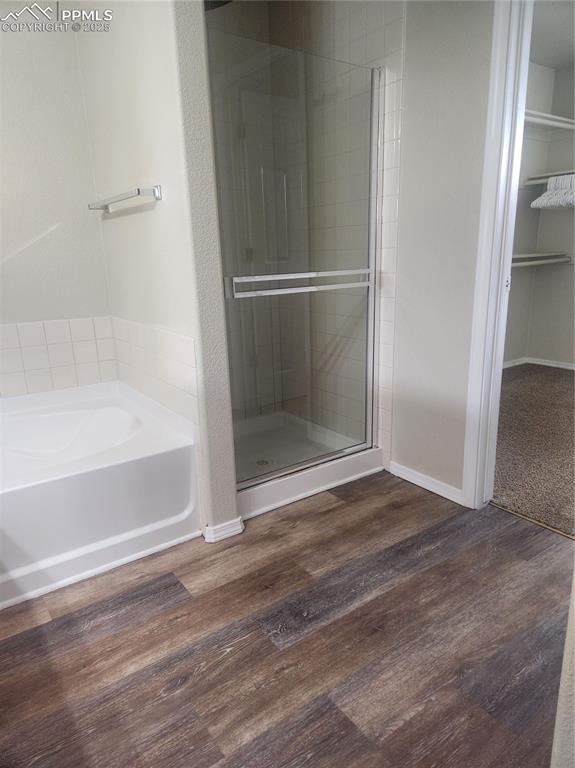 4806 Rusty Nail Point, Unit 202 Colorado Springs, CO 80916 - Photo 19 of 24 Bathroom featuring a garden tub, a stall shower, dark wood-style floors, and a walk in closet