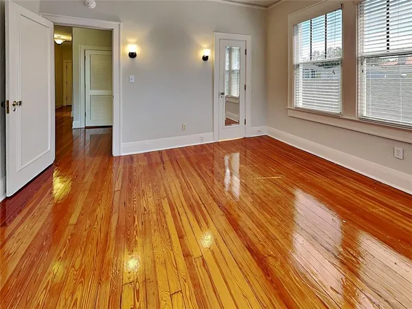 a view of an empty room with wooden floor and a window