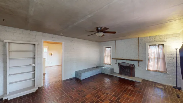 an empty room with wooden floor fireplace and windows