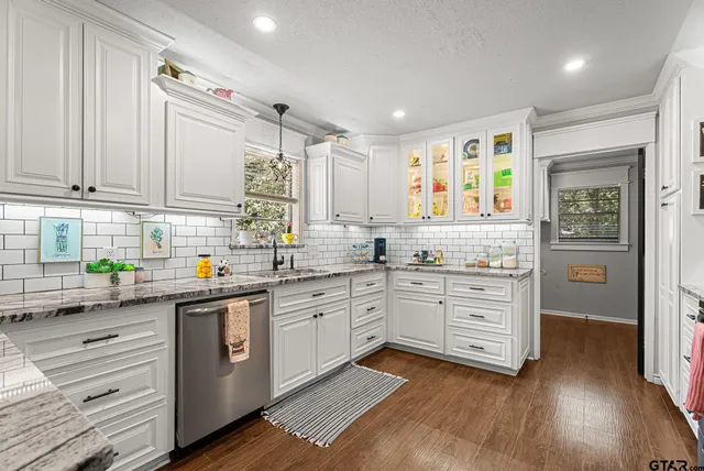 a kitchen with granite countertop a sink cabinets stainless steel appliances and a window