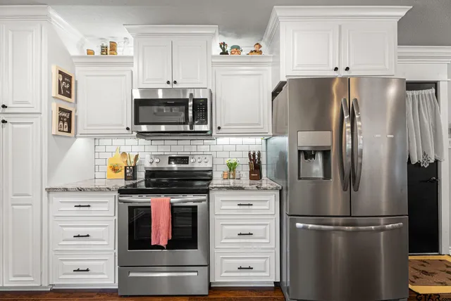 a kitchen with stainless steel appliances white cabinets and a refrigerator