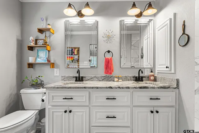 a bathroom with a granite countertop sink vanity mirror and toilet
