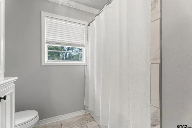 a view of an empty room with window and a ceiling fan