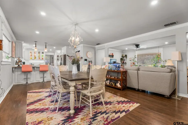 a room with stainless steel appliances kitchen island granite countertop a table chairs and a refrigerator