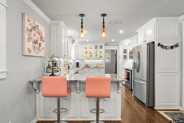 a kitchen with stainless steel appliances kitchen island granite countertop a refrigerator and a dining table