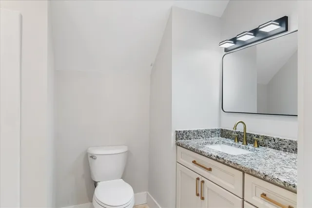a bathroom with a granite countertop toilet sink and mirror