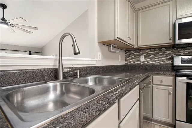 a kitchen with granite countertop white cabinets stainless steel appliances and sink