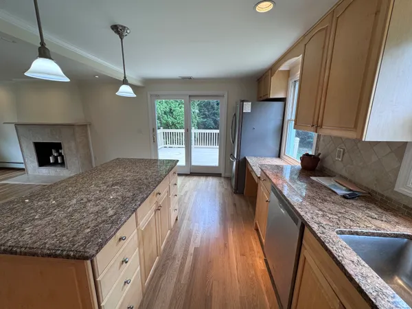 a kitchen with kitchen island granite countertop a sink a counter top space appliances and cabinets