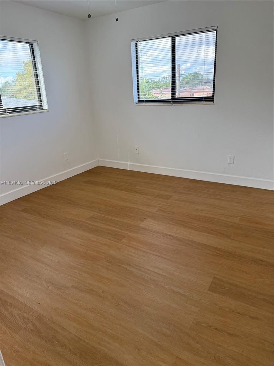180 Northeast 71st Street, Unit 5 Miami, FL 33138 - Photo 11 of 12 a view of a room with wooden floor and window