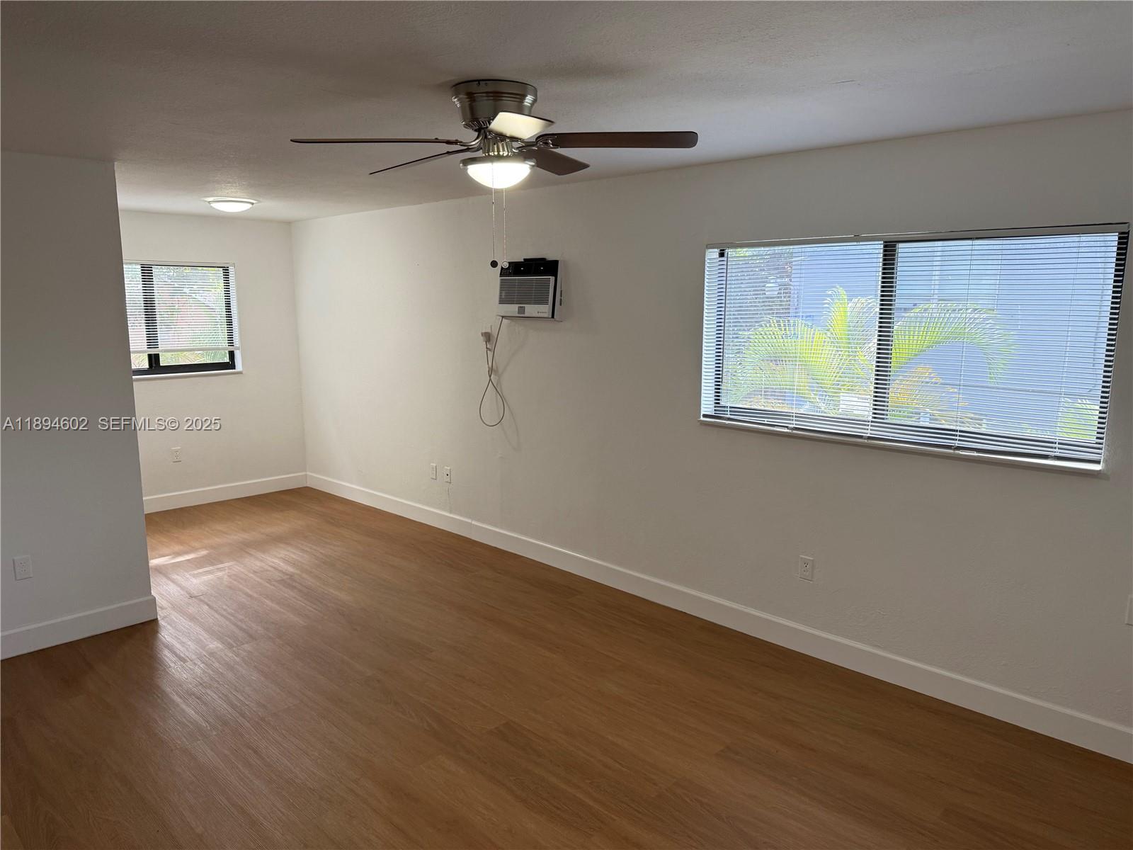 180 Northeast 71st Street, Unit 5 Miami, FL 33138 - Photo 3 of 12 an empty room with wooden floor fan and windows