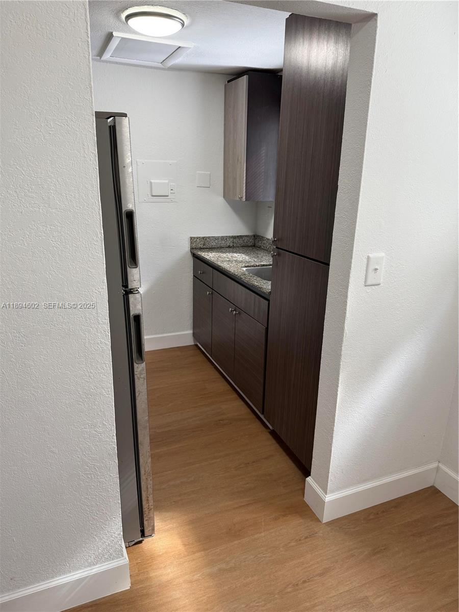 180 Northeast 71st Street, Unit 5 Miami, FL 33138 - Photo 6 of 12 a kitchen with a refrigerator and wooden floor