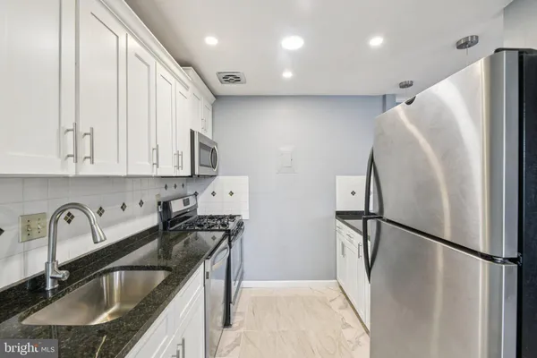 a kitchen with stainless steel appliances granite countertop a refrigerator a sink a stove and a sink with wooden floor