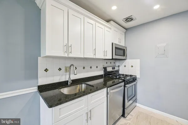 a kitchen with granite countertop a sink and white cabinets