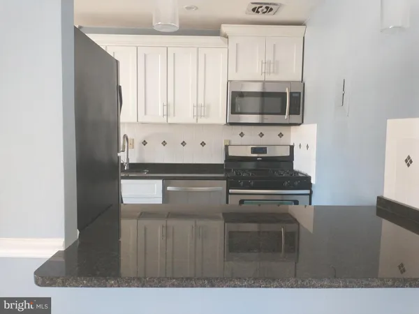 a kitchen with granite countertop a stove and a microwave