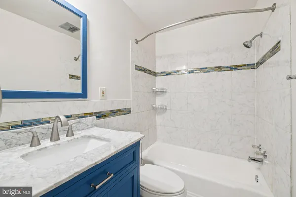 a bathroom with a granite countertop sink mirror toilet and bathtub
