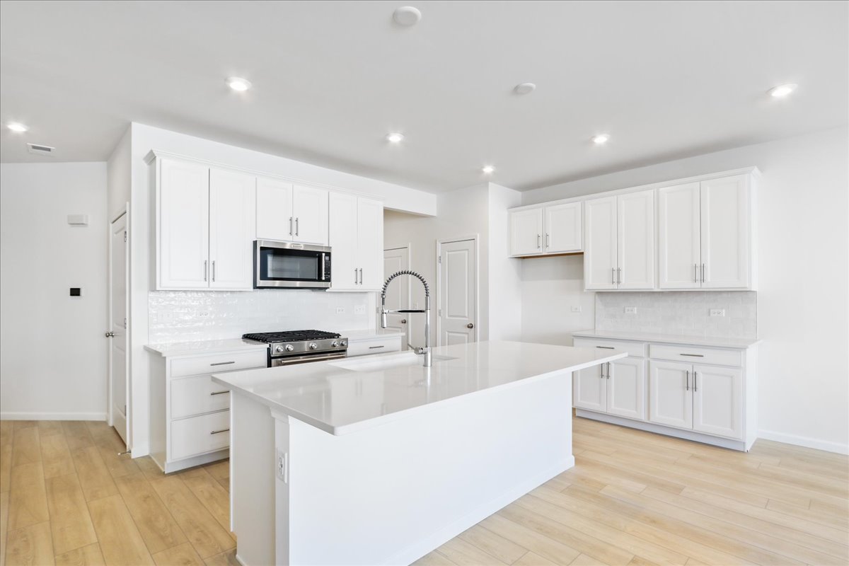 644 Switchgrass Way, Unit 59002 Bolingbrook, IL 60490 - Photo 5 of 26 a large kitchen with stainless steel appliances granite countertop a stove a sink a refrigerator and white cabinets with wooden floor
