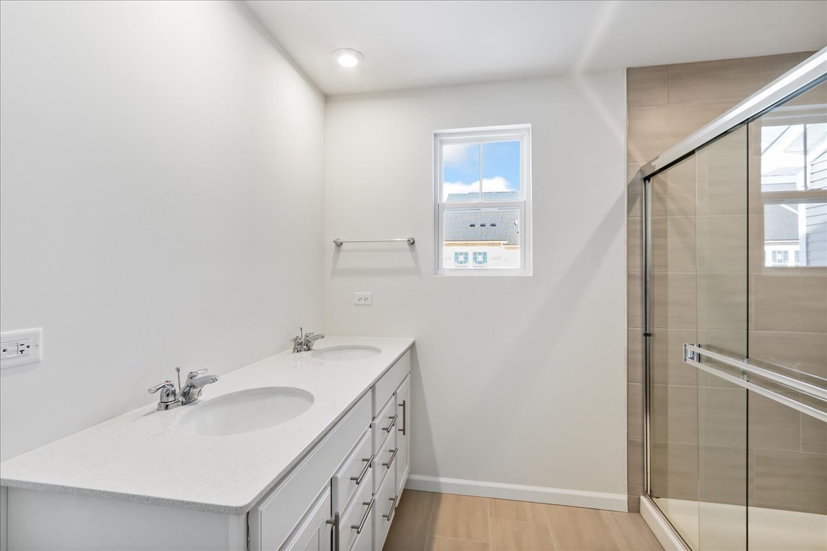 644 Switchgrass Way, Unit 59002 Bolingbrook, IL 60490 - Photo 18 of 26 a bathroom with a sink a mirror and a shower