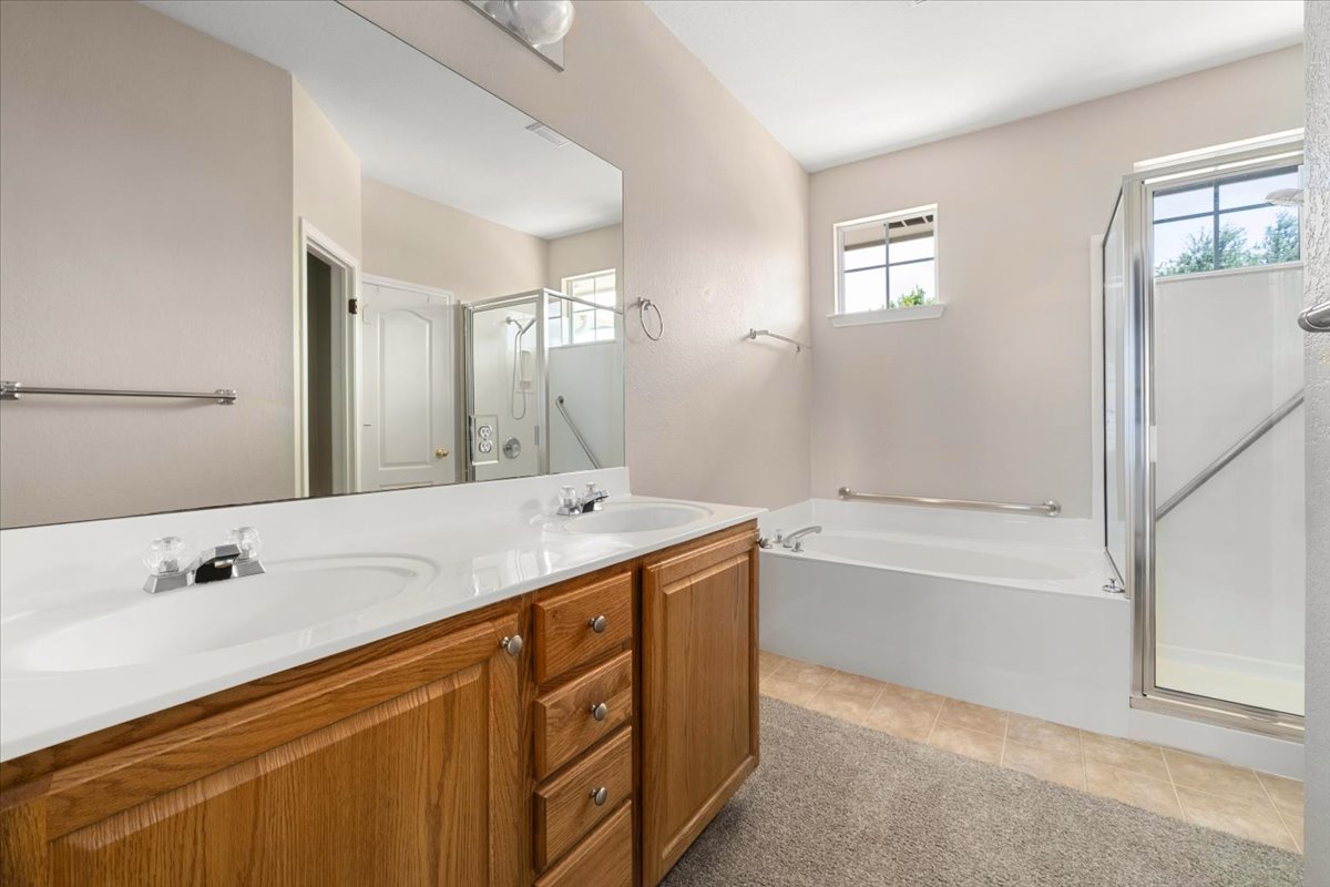 11000 Anderson Mill Road, Unit 11 Austin, TX 78750 - Photo 14 of 34 Double vanity sinks and a separate tub and shower offer everyday convenience in this bright bathroom.