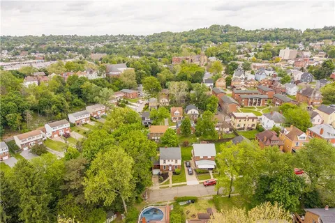 an aerial view of residential houses with outdoor space and trees