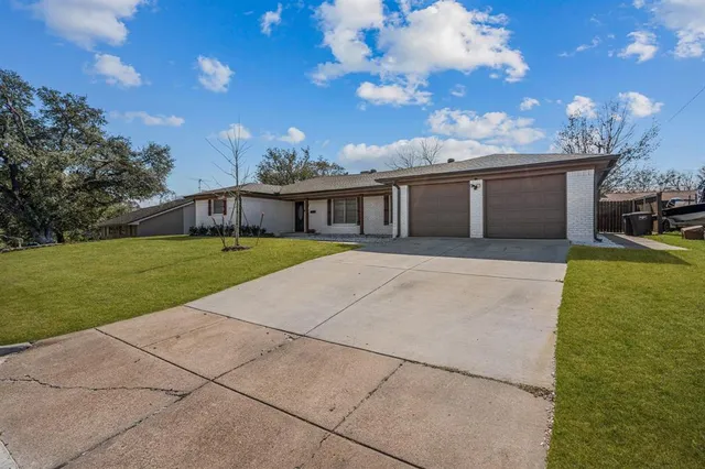 a view of a house with a yard and large tree