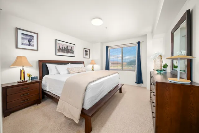 a spacious bedroom with a bed and a lamp on a dresser
