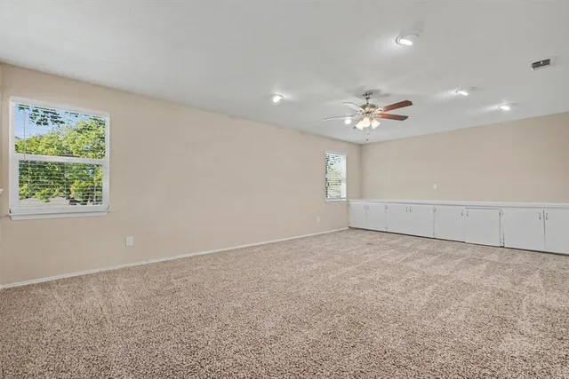 an empty room with windows and chandelier fan