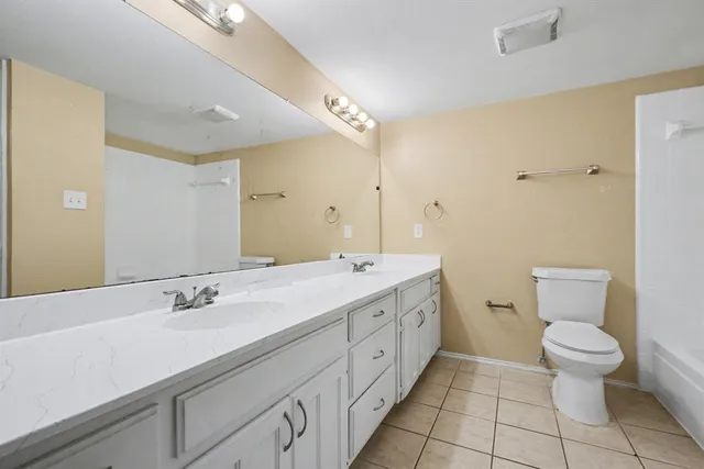 a bathroom with a double vanity sink toilet and a mirror
