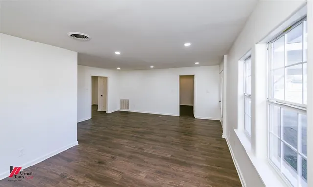a view of a big room with wooden floor and windows