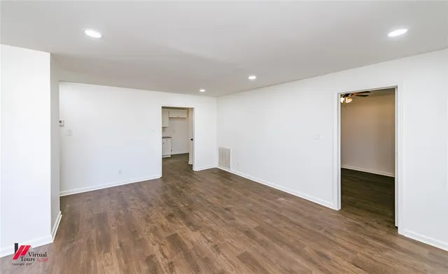 a view of an empty room with wooden floor and closet