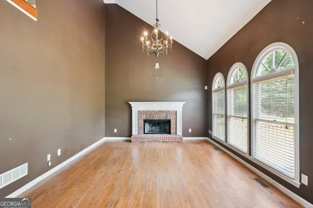 a view of a livingroom with a fireplace wooden floor and windows