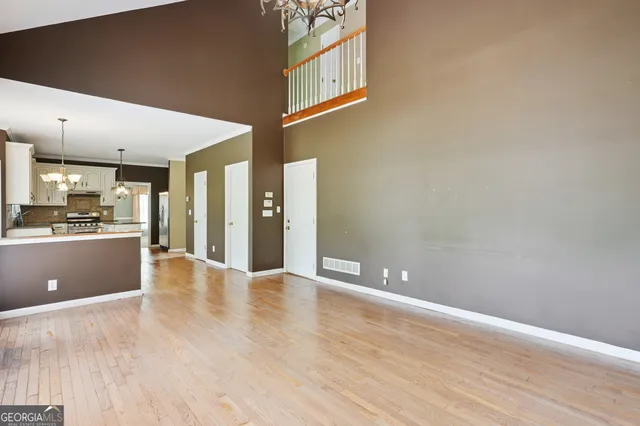 a view of an empty room with kitchen view and a window