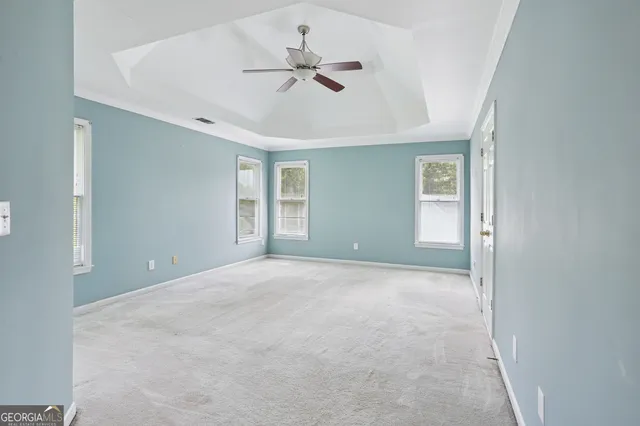 an empty room with ceiling fan and window