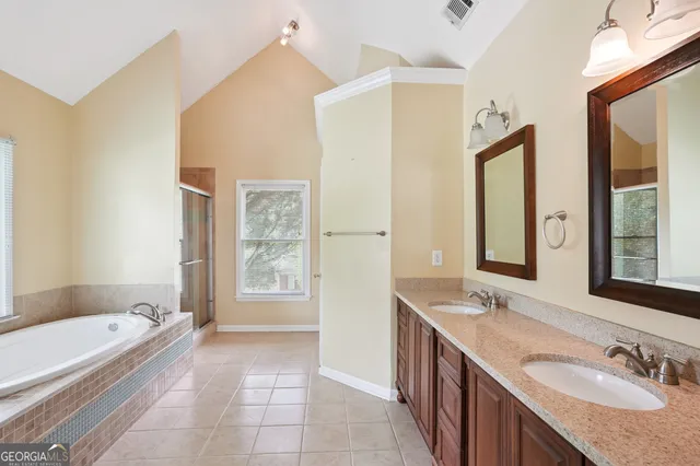 a bathroom with a granite countertop tub sink and mirror