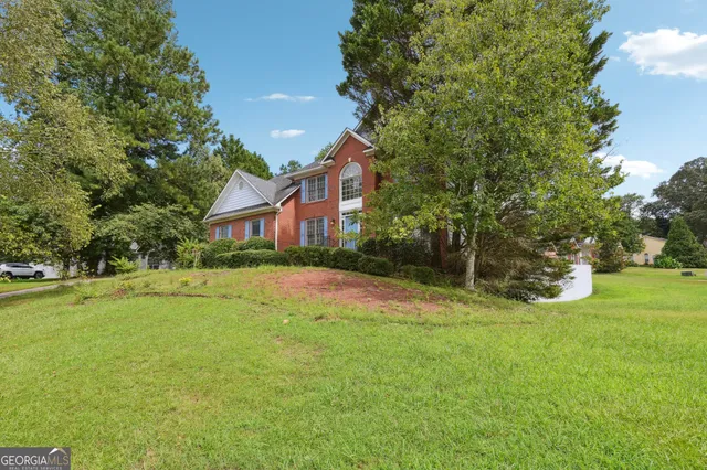a view of an house with backyard and a tree