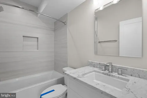 a bathroom with a granite countertop sink a toilet and shower