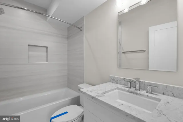 a bathroom with a granite countertop sink a toilet and shower
