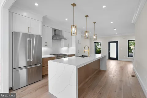 a large kitchen with stainless steel appliances kitchen island granite countertop a refrigerator a oven a island and a sink with large countertops